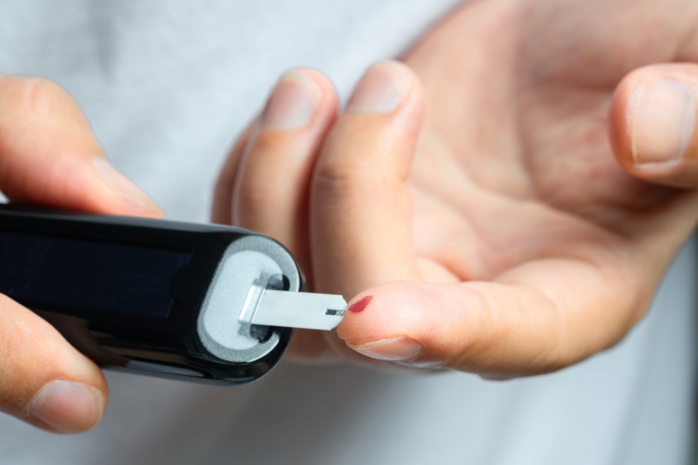 A man draws blood on his finger and tests it for diabetes. Check high blood sugar levels with a digital blood sugar tester. Health care and medical concept